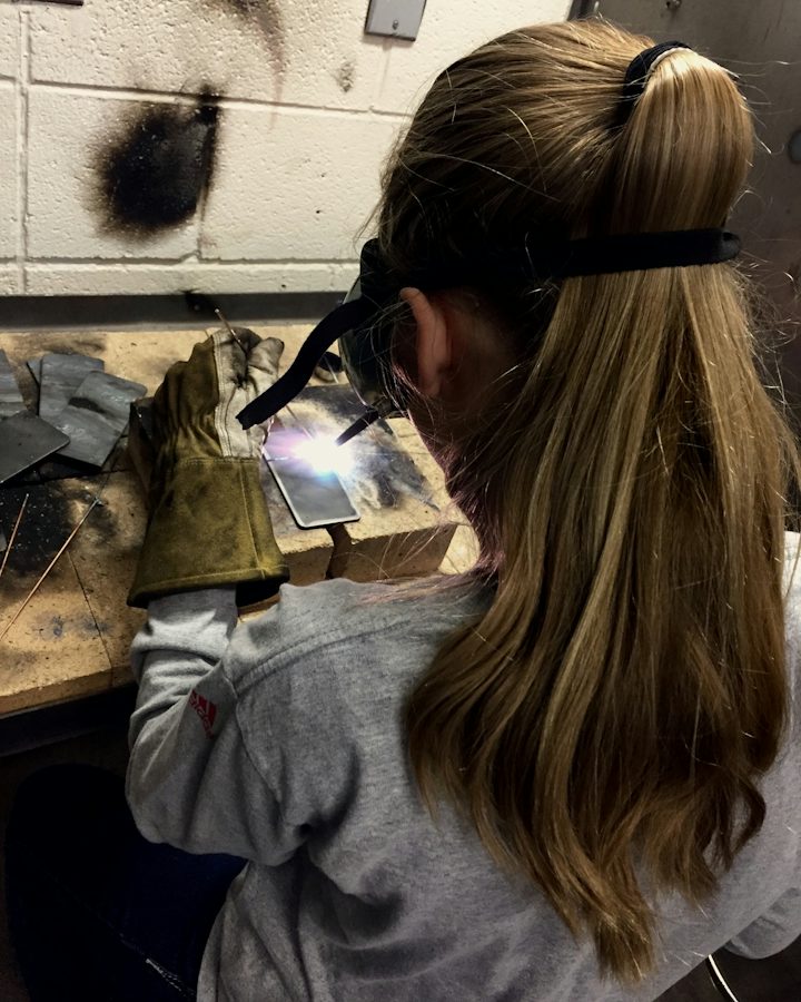 Apprentice welding at a bench